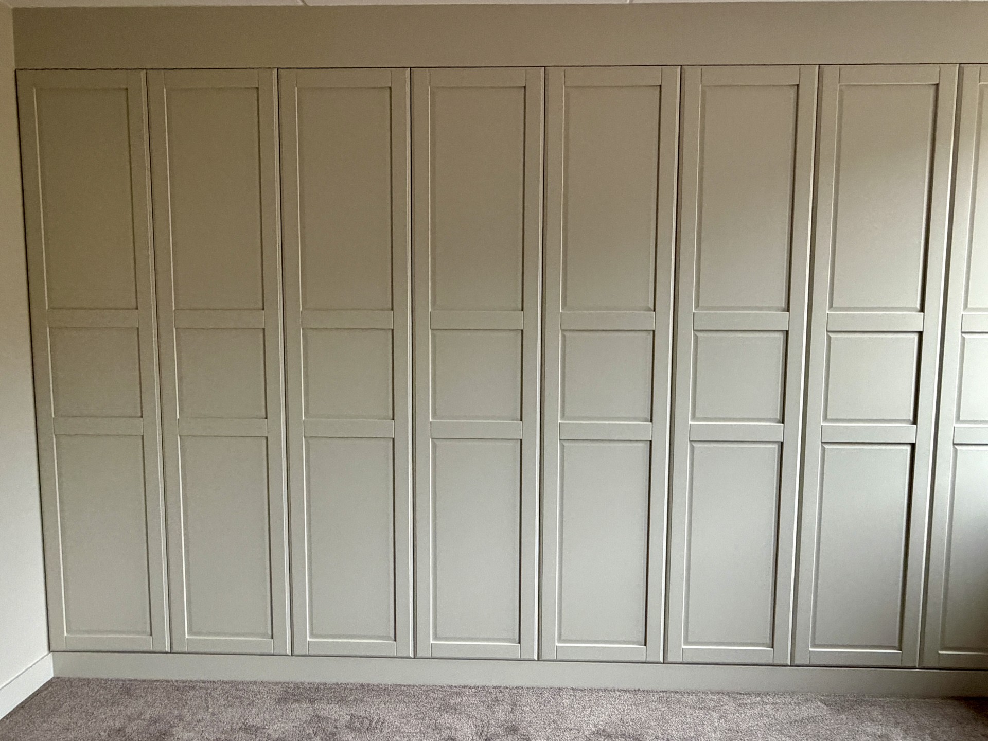 ae6dbf97-8b3f-4ec5-b241-d652514dc754 Strak afgewerkte inbouwkast op maat met paneeldeuren en meegeschilderde ombouw in dezelfde kleur als wand en plinten voor een luxe uitstraling.